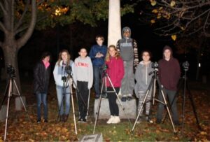 teens pose with tripods near a monument
